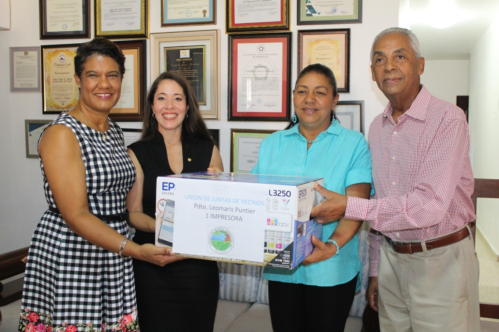 Rossy Ruíz, Ariadna Méndez y José Tejeda entregan una computadora a Leomaris Puntiel, presidenta de la Unión de Juntas de Vecinos de Jarabacoa