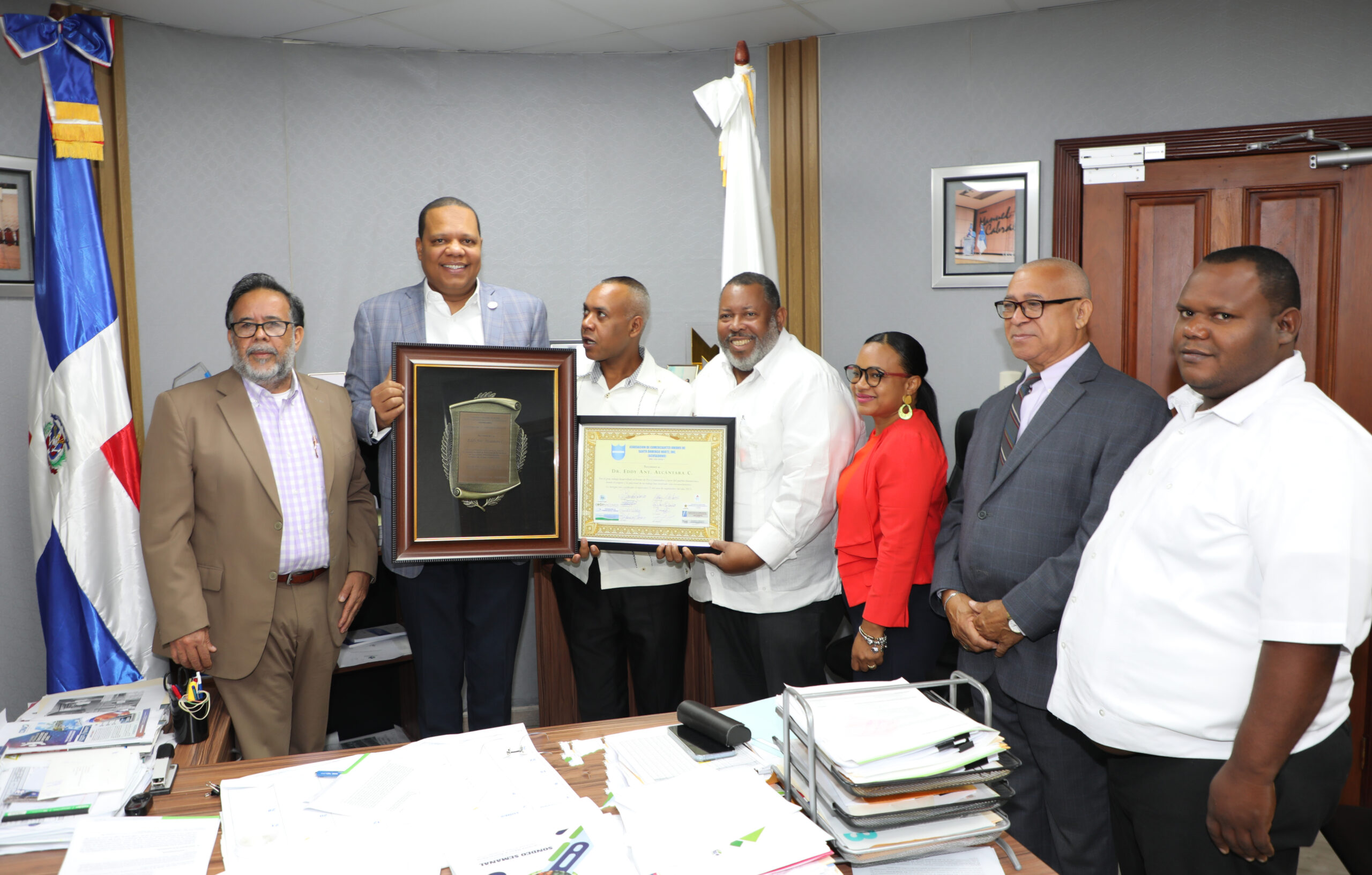 El director de Pro Consumidor, Eddy Alcántara, momento en que recibe las placas de reconocimiento por parte de los comerciantes.