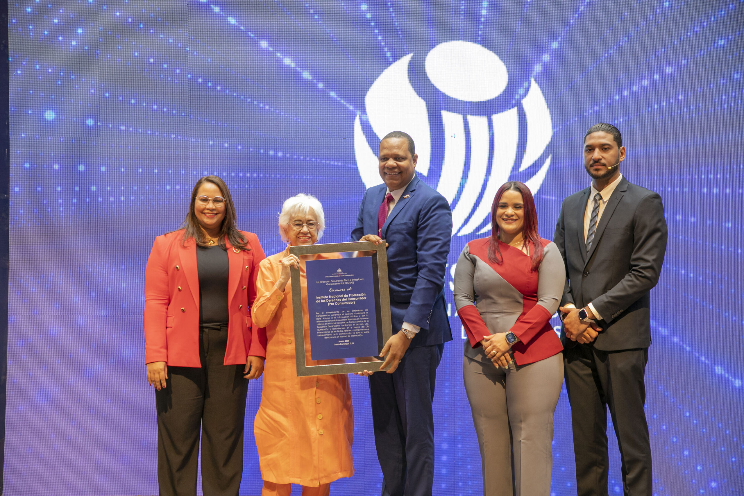 Titular De La Direccion General De Etica Gubernamental Milagros Ortiz Bosch Entrega Placa De Reconocimiento Al Director Ejecutivo De Pro Consumidor Eddy Alcantara Scaled